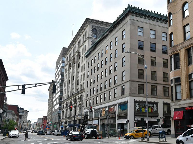 Large urban building, grey, 6-7 stories, street level businesses