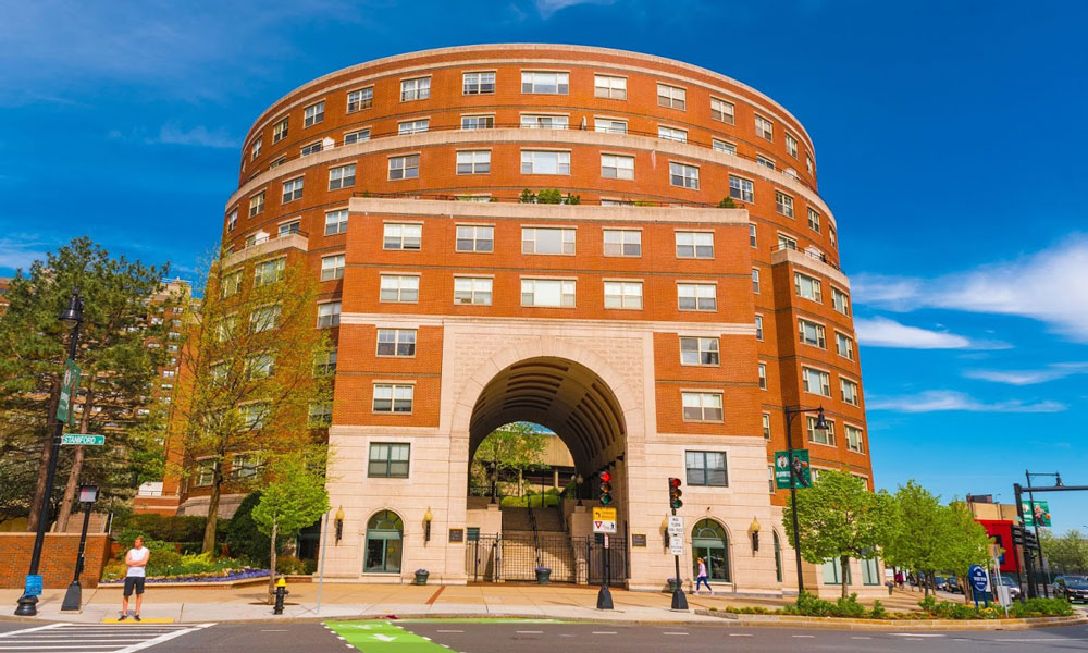 Ten story, round, brick building with some balconies and a grand arched entryway