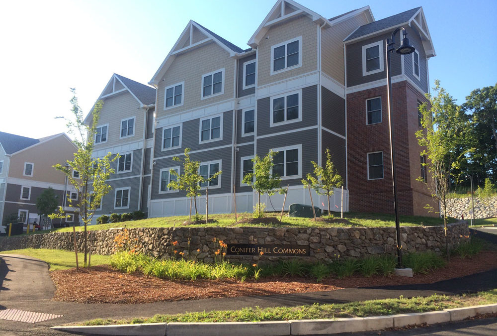 Three story apartment buildings, pitched roofs, clapboard siding, nice landscaping