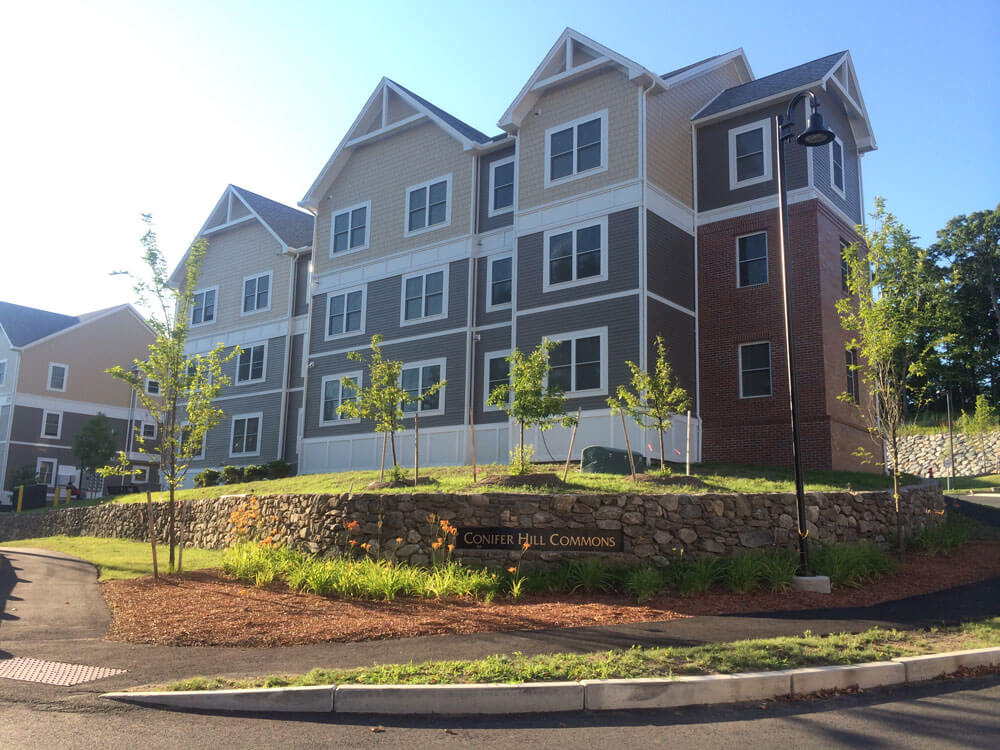 Three story apartment buildings, pitched roofs, clapboard siding, nice landscaping