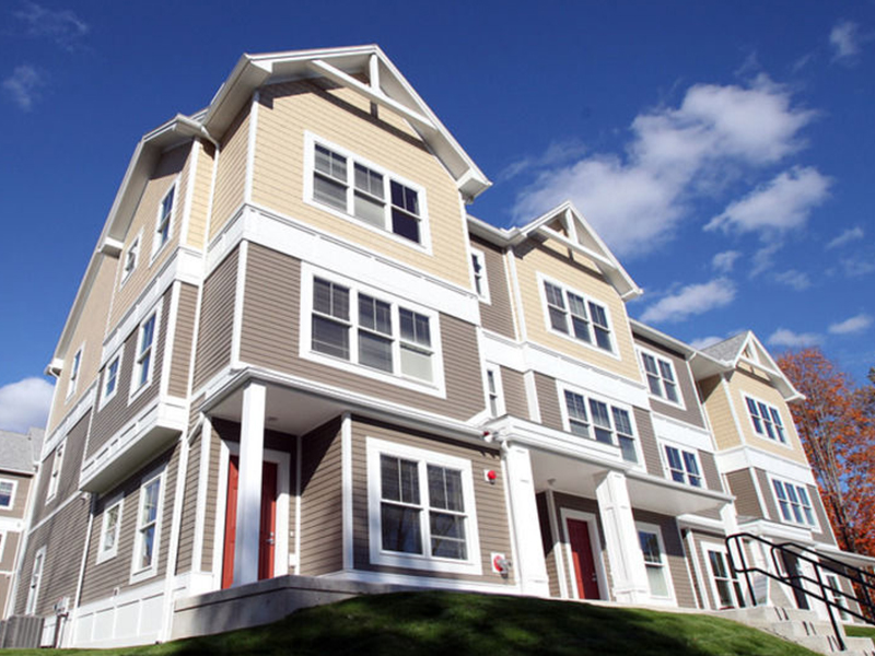 Street view of 3 story apartment buildings. Pitched roofs, clapboard siding, modern colonial look.